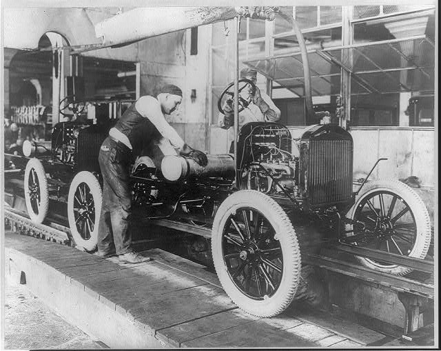 Workers stationed along an early Ford Motor Company assembly line